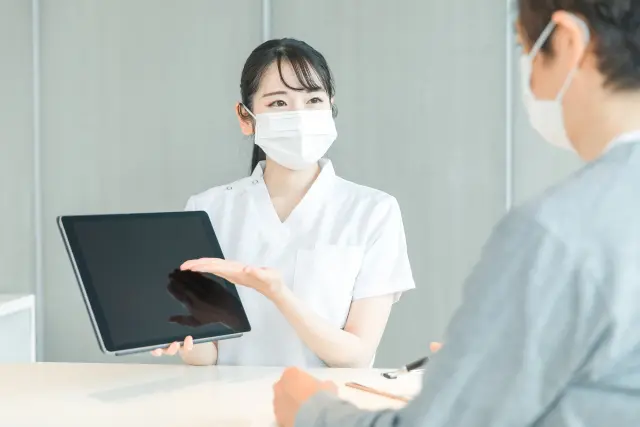 タブレットPCで受付する白衣の女性と患者